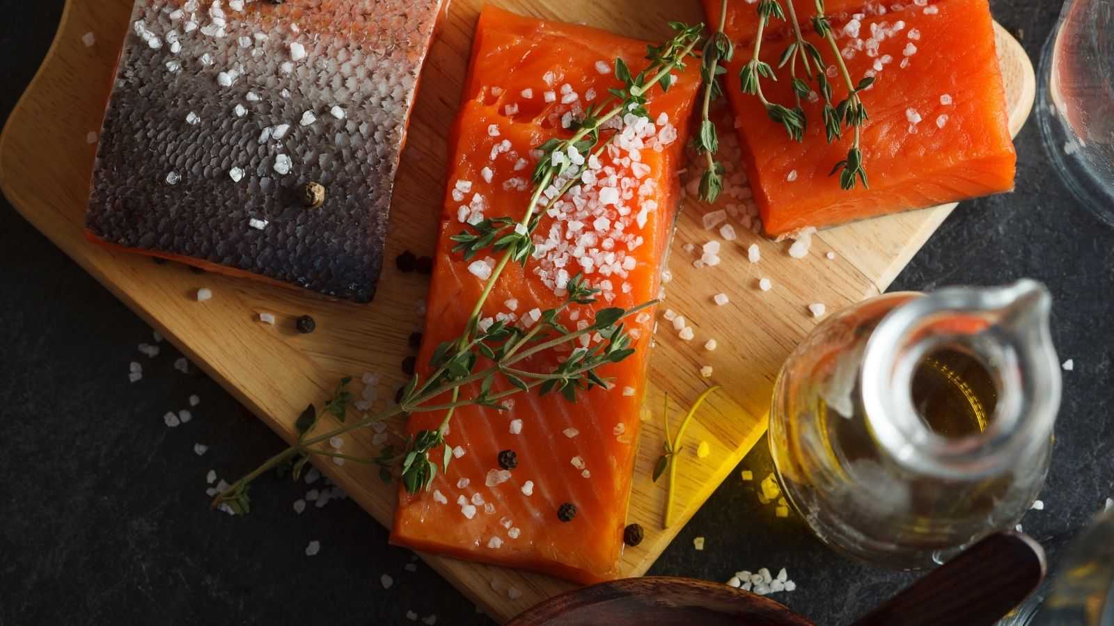 Raw salmon fillets sprinkled with salt and fresh herbs