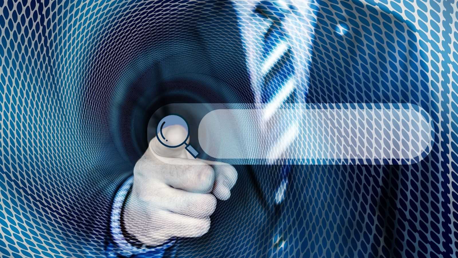 A man wearing a suit, tie and shirt, his finger touches the magnifying glass icon