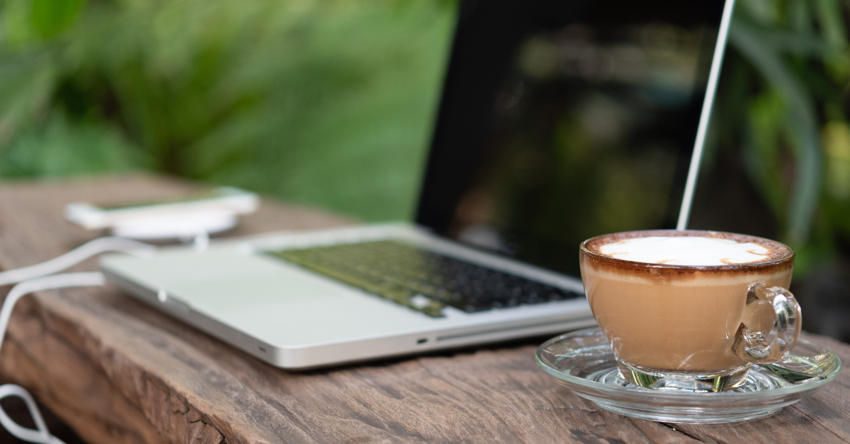 Laptop on table next to coffee in a cup