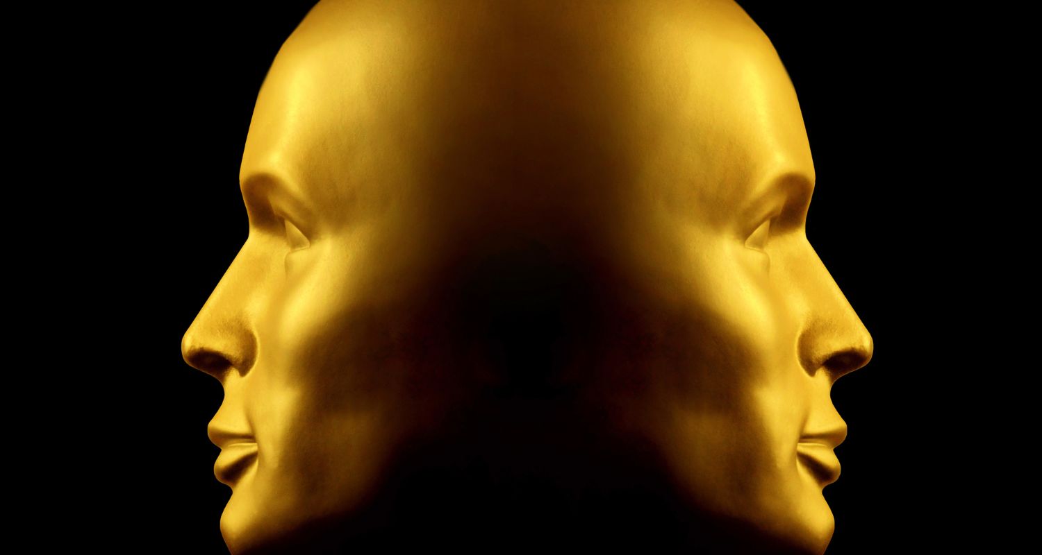 A golden sculpture of two heads joined at the back of the head