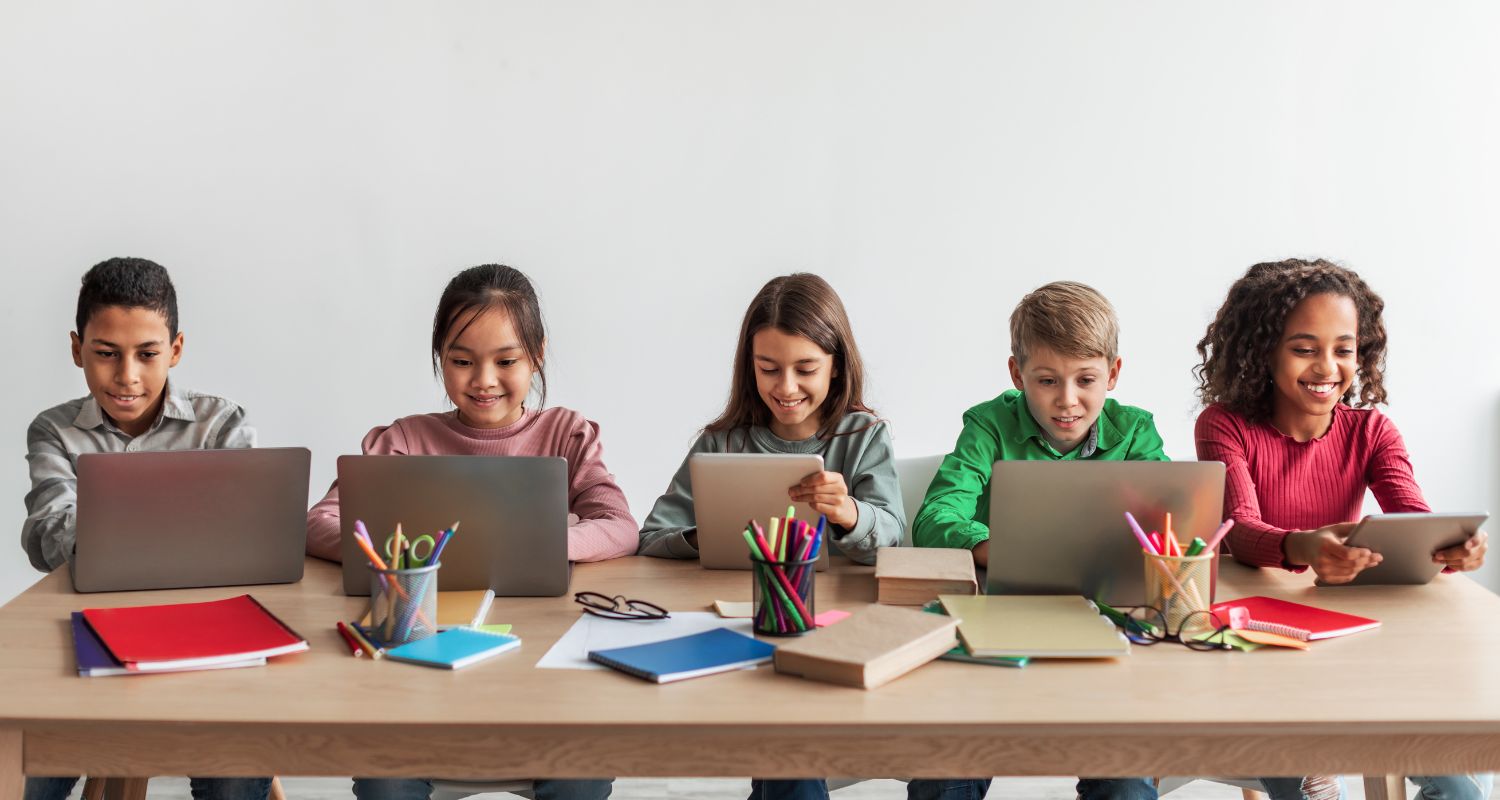 Five children learning on tablets and laptops