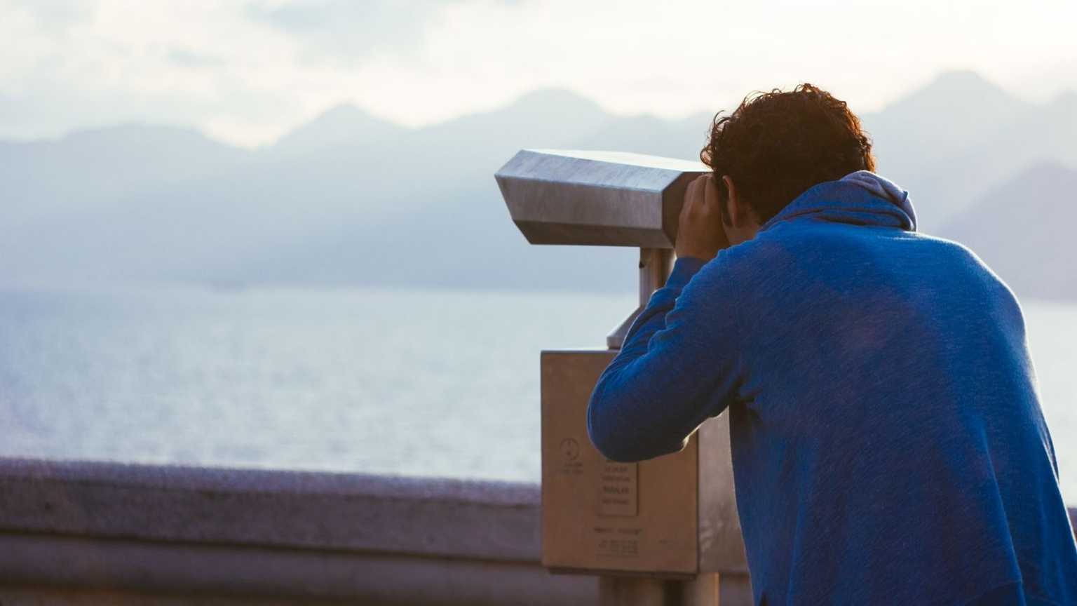 A person looking into the distance through large binoculars